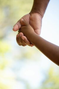 A close up of a child holding the hand of their parent. This could represent the bonds cultivated after child counseling in Boulder, CO. Learn more about how a psychotherapist in boulder co can offer support with online therapy in colorado. 