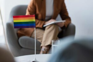 A close up of a flag on a desk as a person takes notes. This could symbolize meeting with a LGBTQ therapist in Boulder, CO. Learn more about Boulder therapists and how LGBTQ therapy in Boulder, CO can offer support. Search for LGBTQ counseling in Boulder, CO to learn more. 