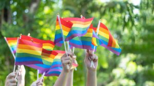 A close up of hands holding up pride flags. Learn how LGBTQ therapy in Boulder, CO can offer support by searching for an online therapist in Boulder, CO. They can offer remote LGBTQ counseling in Boulder, CO and other services.