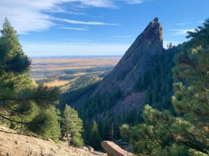 An image of a large rock formation towering a valley with a trail off in the distance. You can get support anywhere in Colorado via online therapy in Boulder, CO. A therapist in Boulder, CO can offer support with telehealth in Boulder, CO and more. 