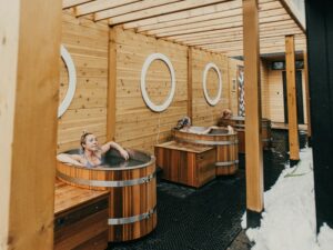 People smile while relaxing in wooden ice baths along a wall. This could represent a form of stress relief that an anxiety therapist in Boulder, CO can help you cultivate. Learn more about anxiety treatment in Boulder, CO by searching for anxiety therapist Boulder or Boulder counseling today.