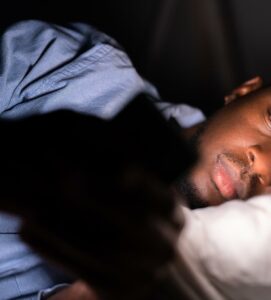 A man laying in bed types on their phone in the dark. This could represent a screen addiction that a therapist in Boulder, CO can help you address. Learn more about online therapy in Colorado and how mindfulness based cognitive therapy in Boulder, CO can help you create a healthier relationship with technology. 
