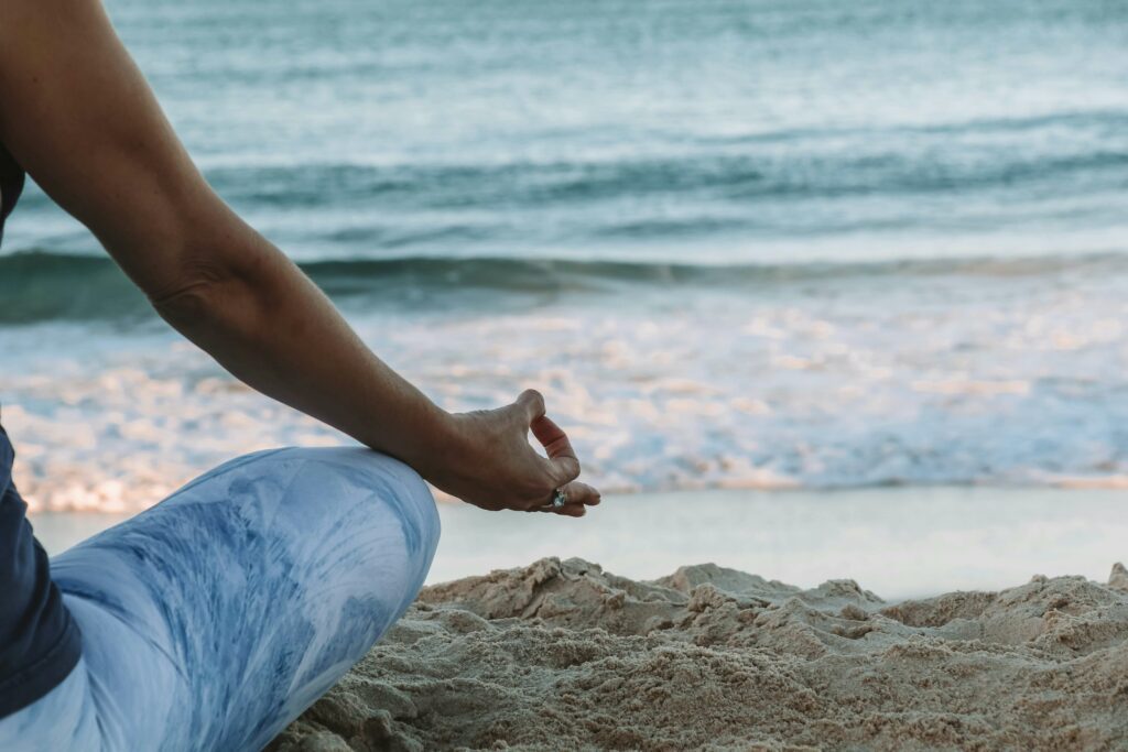 A close up of a person sitting on the beach next to the waves while meditating. Learn more about mindfulness in Boulder, CO and how a therapist in Boulder, CO can offer support in realizing the benefits of yoga. Search for how to overcome stress symptoms in Boulder, CO today.
