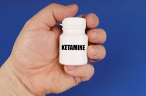 A close up of a person holding a pill bottle with the word ketamine on it. This could represent the benefits of ketamine therapy in Boulder, CO that a psychotherapist in Boulder CO can offer support with. Learn more about addressing treatment resistant depression in Boulder, CO by contacting a ketamine therapist in Boulder, CO today.