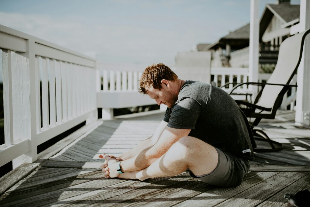 A man stretches while practicing yoga on a deck. Learn more about online therapy in Colorado and how a therapist in Boulder, CO can offer support. Search for mindfulness based therapy in Boulder, CO can offer support with overcoming stress symptoms in Boulder, CO today. 
